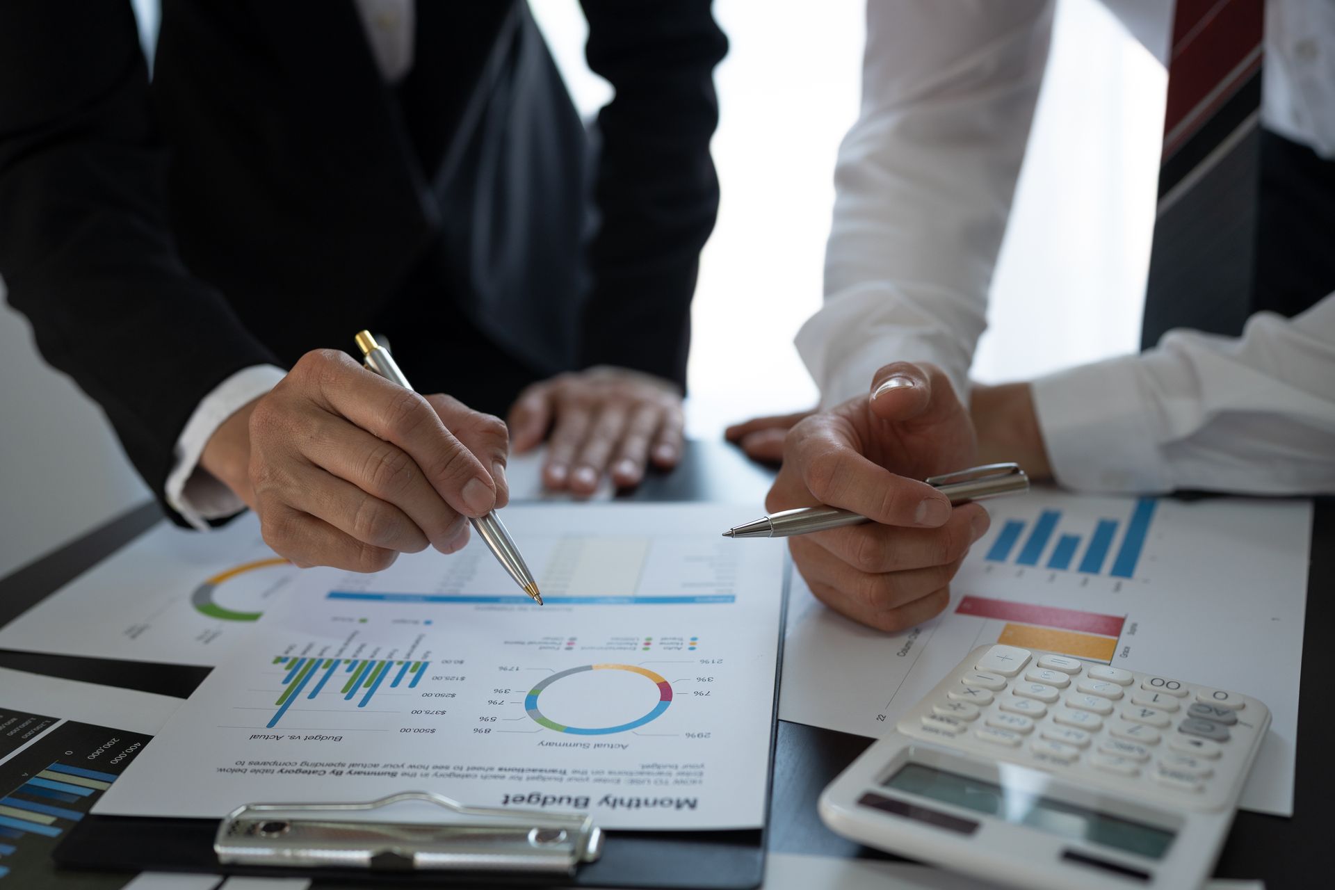 A group of business people are sitting at a table looking at a graph.