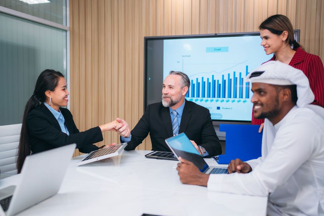 A group of business people are shaking hands in a conference room.