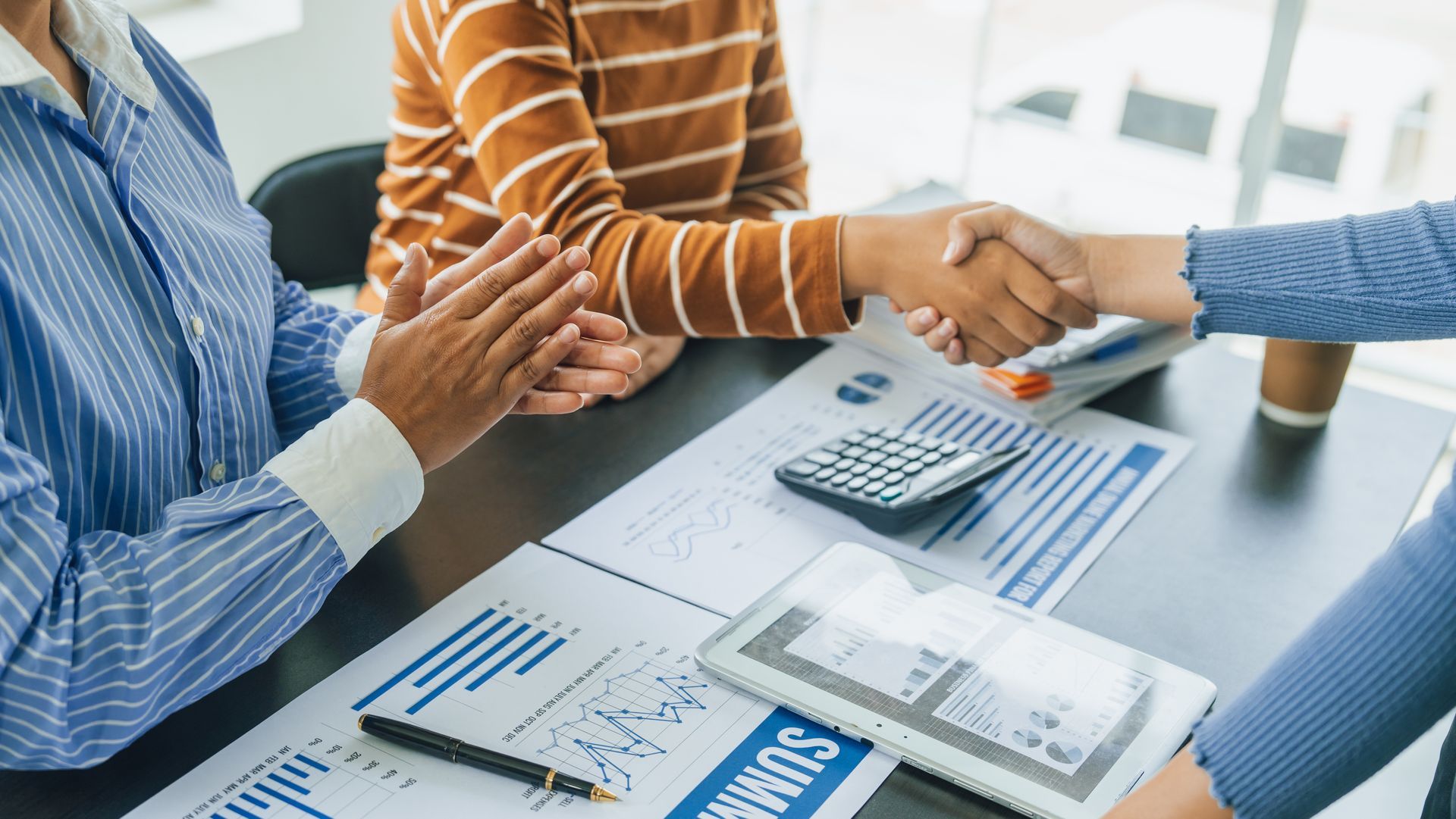 A group of people are shaking hands over a table.