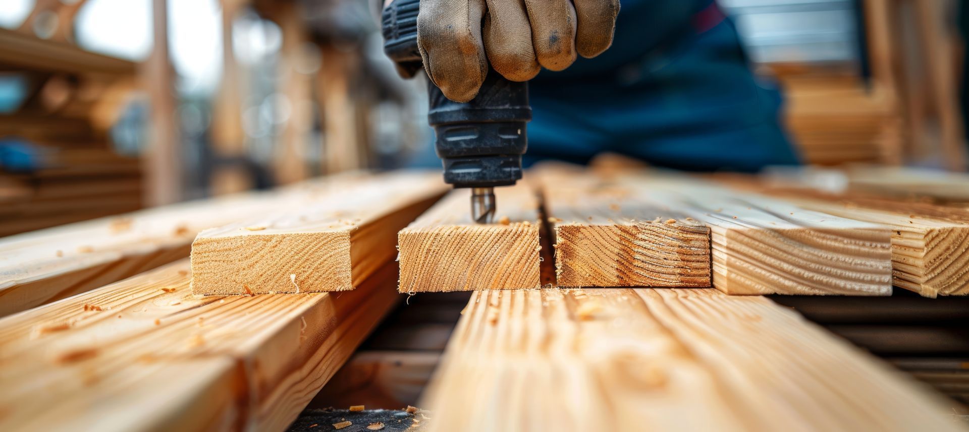 A person using a drill to make a hole in a wooden plank.