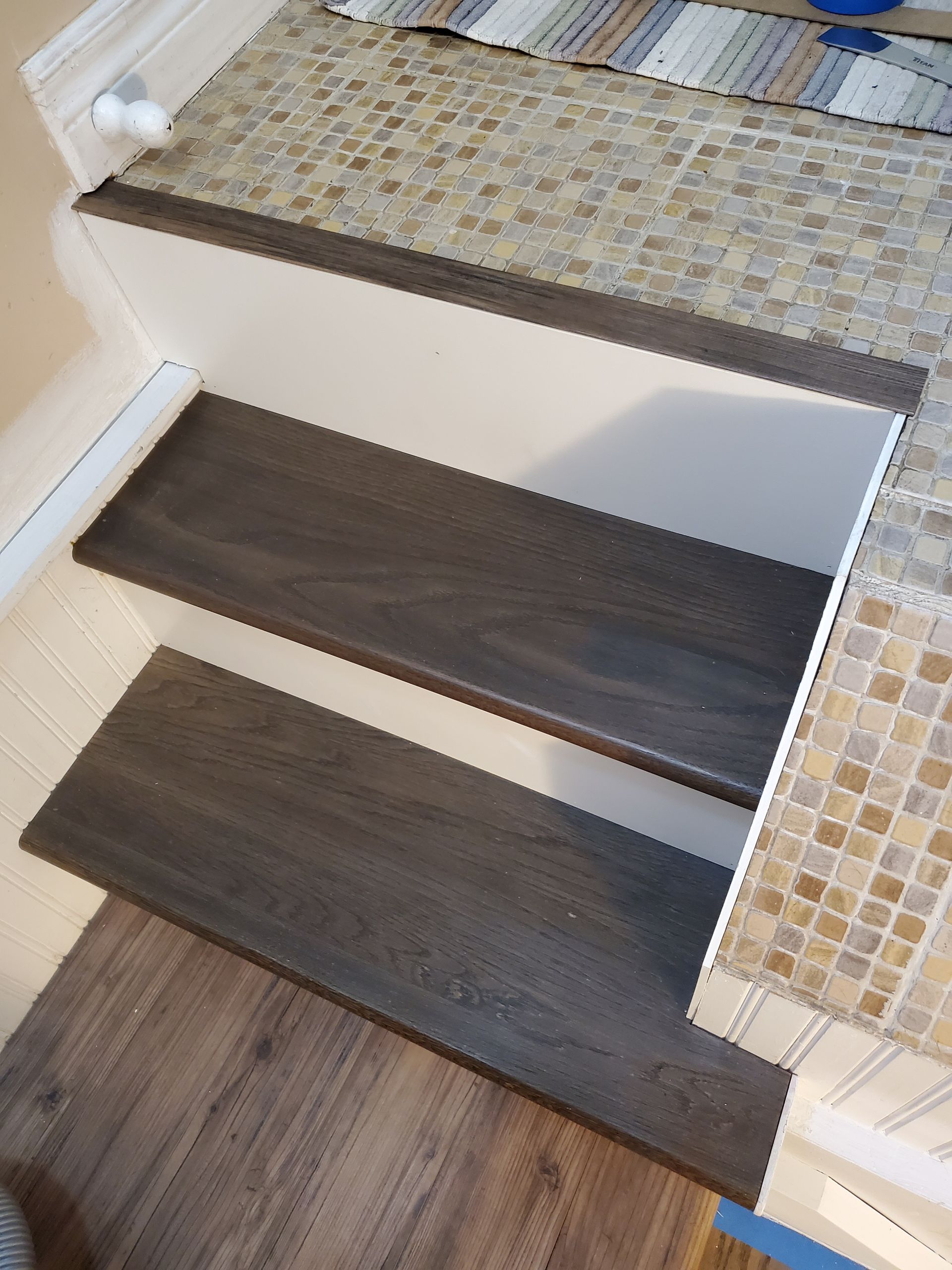A set of wooden stairs leading up to a tiled floor.