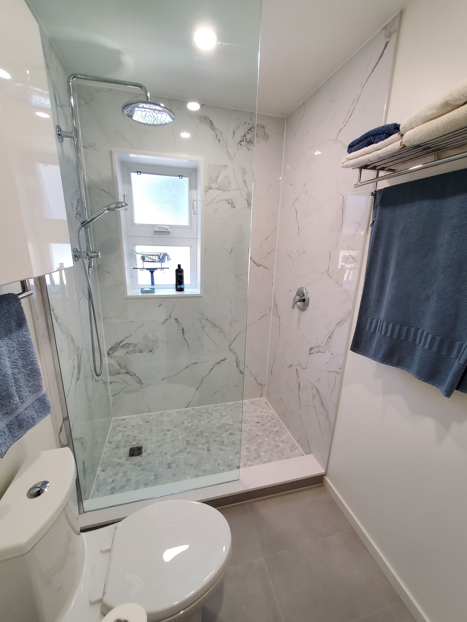 A bathroom with a toilet , shower , and window.