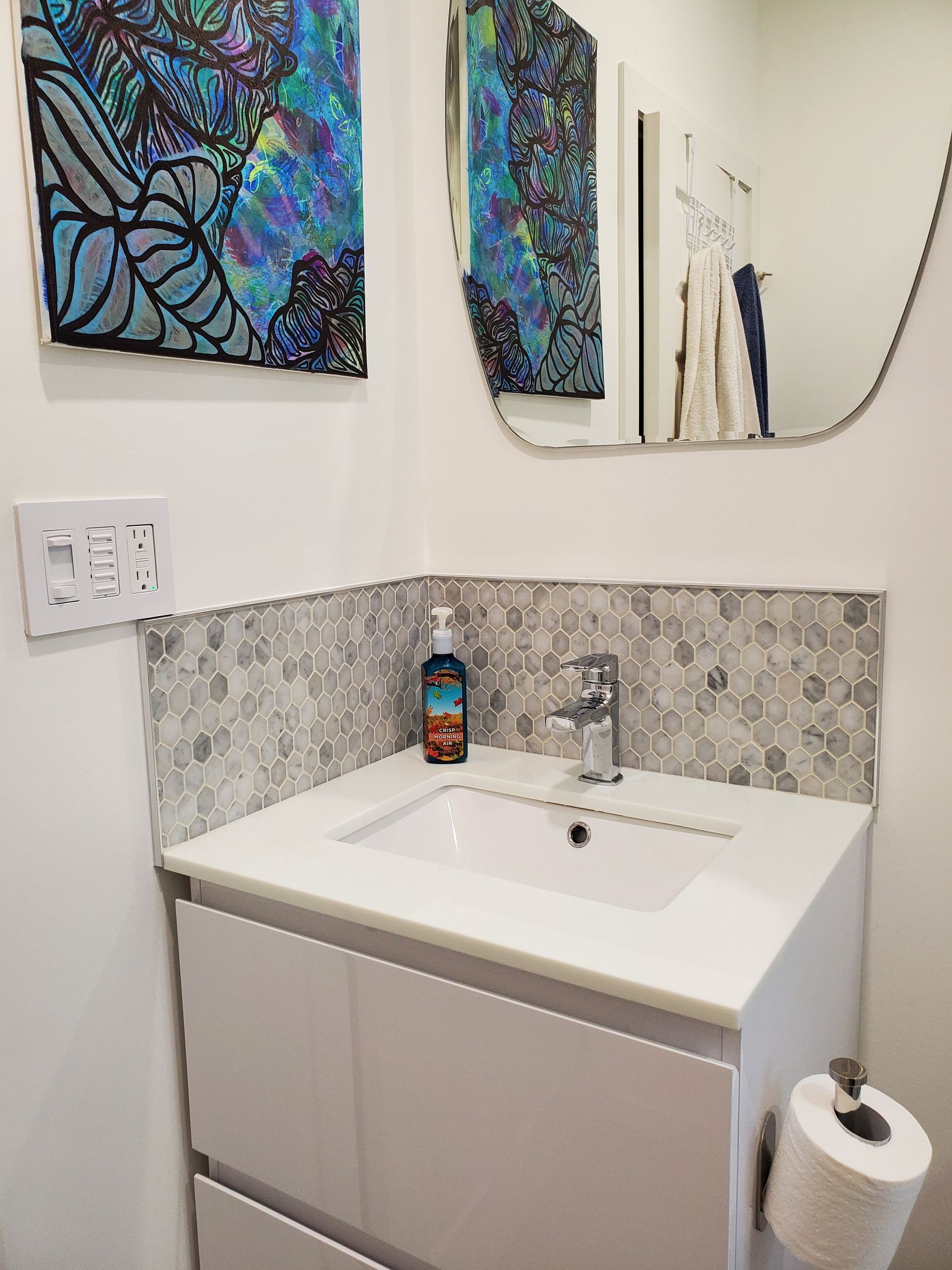 A bathroom with a sink , mirror and toilet paper.