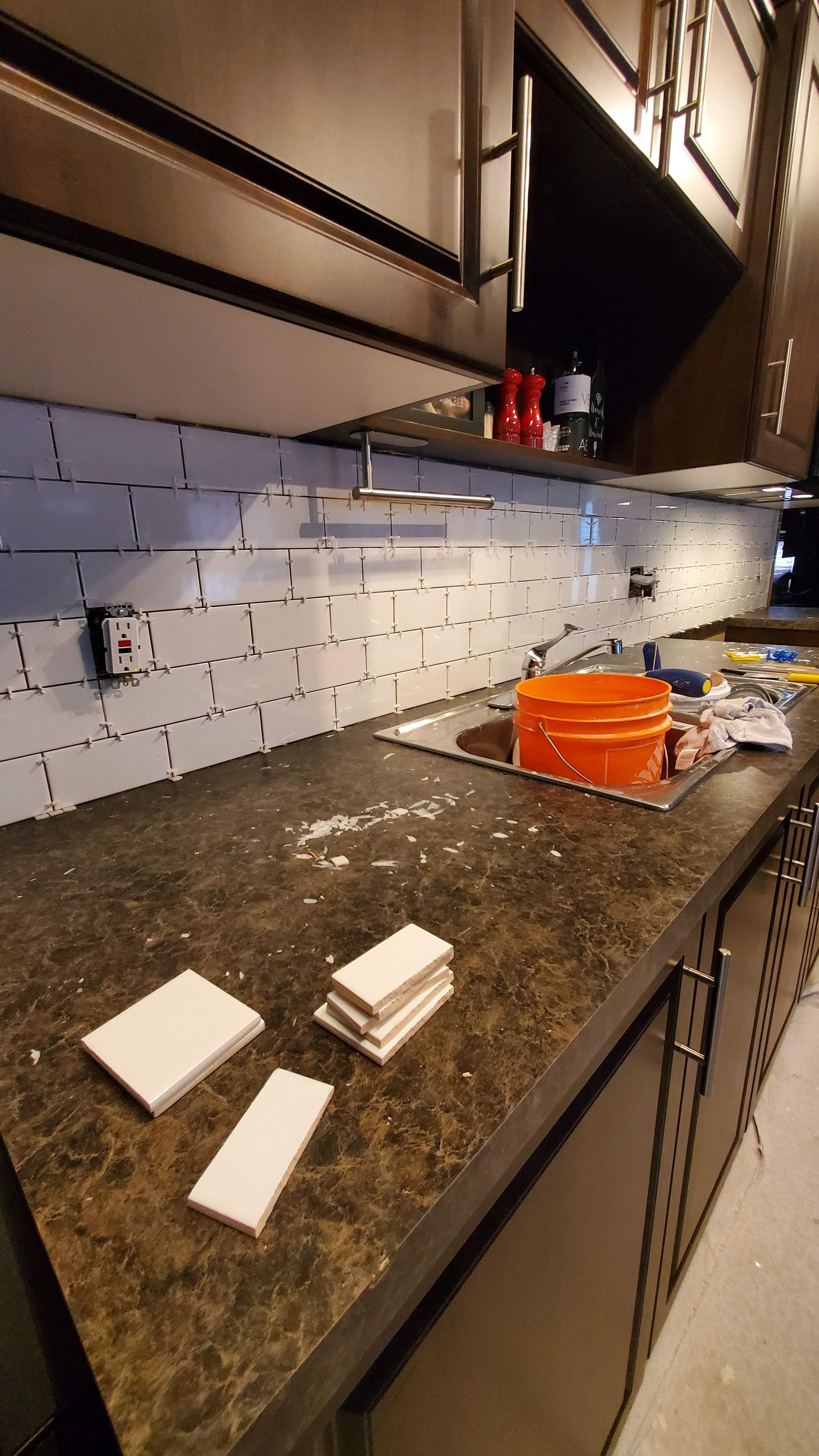 A kitchen counter with a sink and a bucket on it.