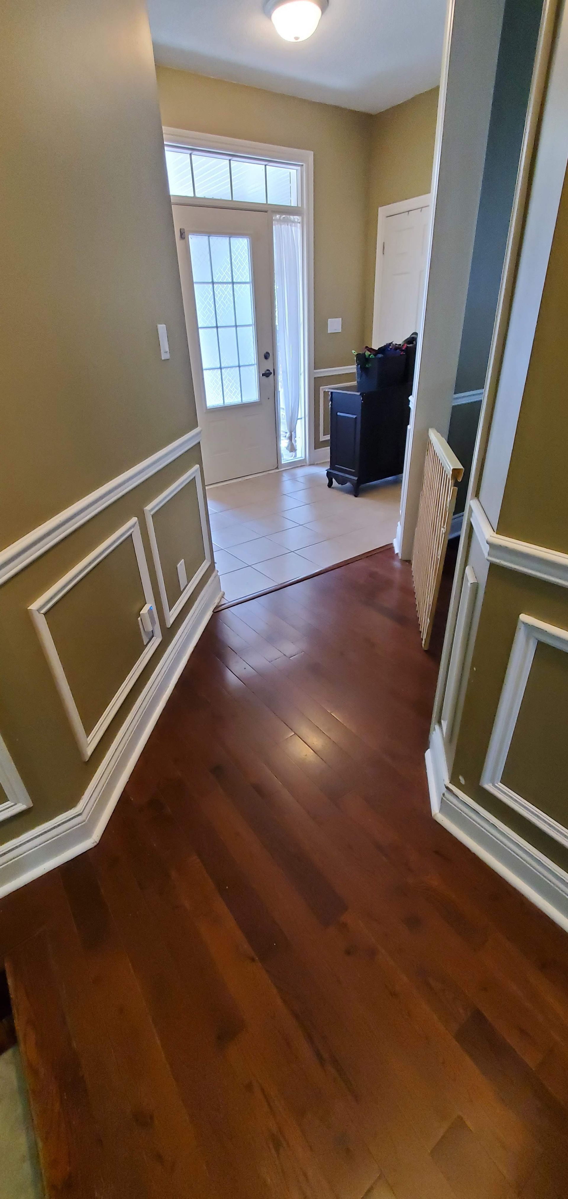 A hallway in a house with hardwood floors and a sliding glass door.