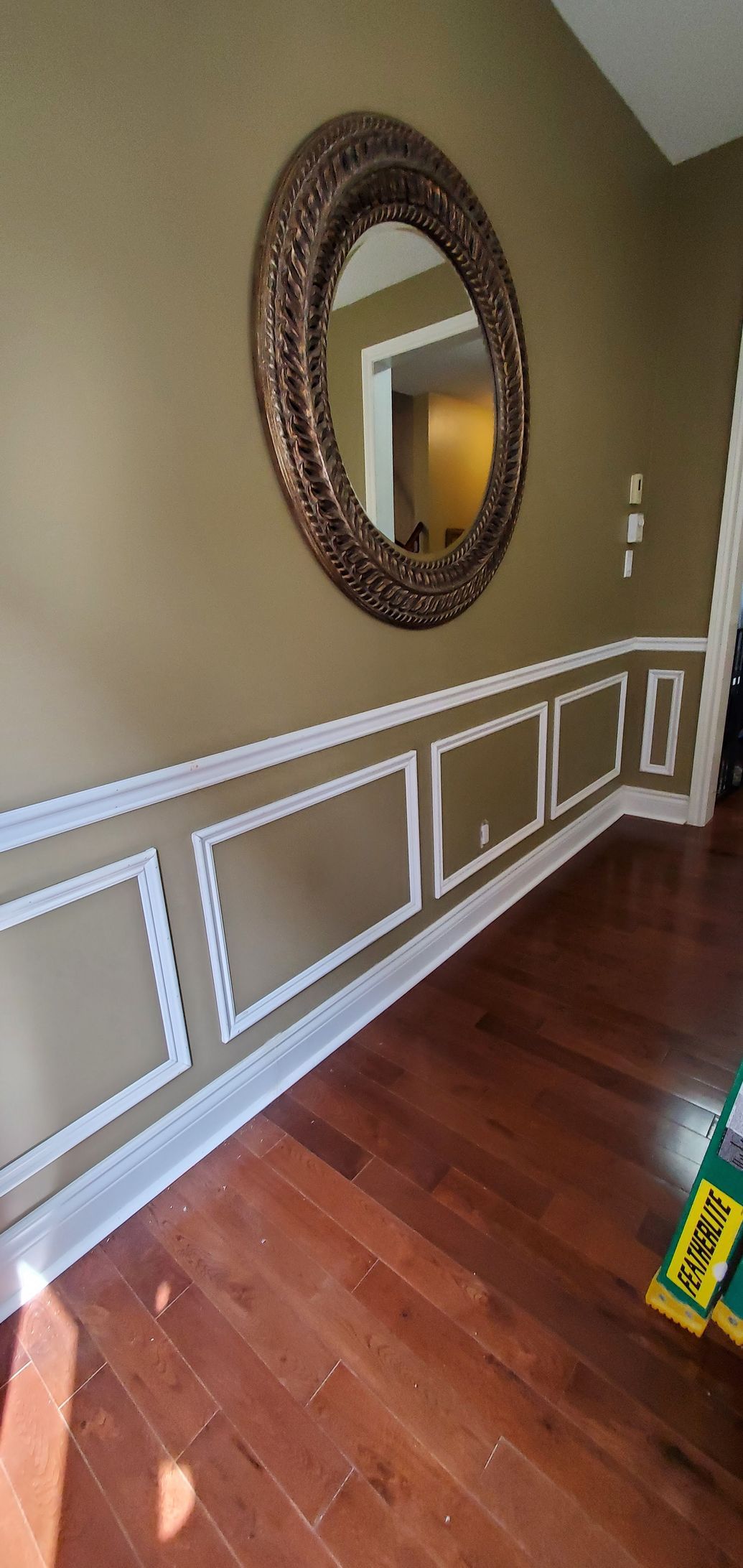 A living room with hardwood floors and a mirror on the wall.