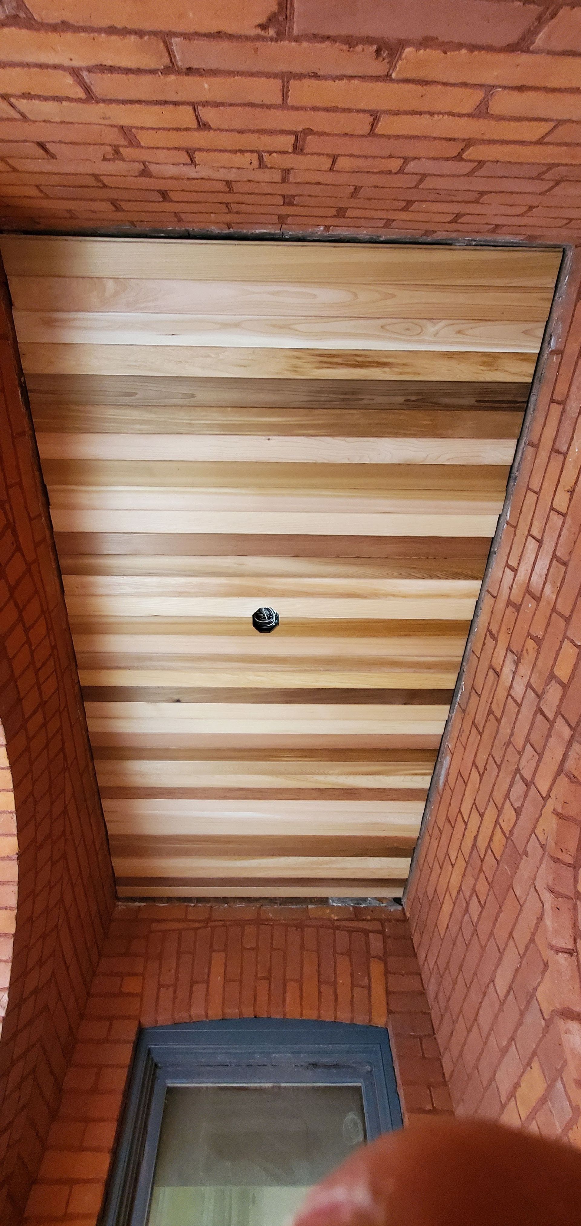 A person is holding a wooden ceiling in a brick building.