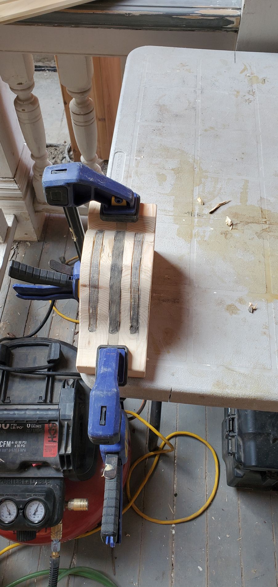 A piece of wood is sitting on top of a table next to a vacuum cleaner.