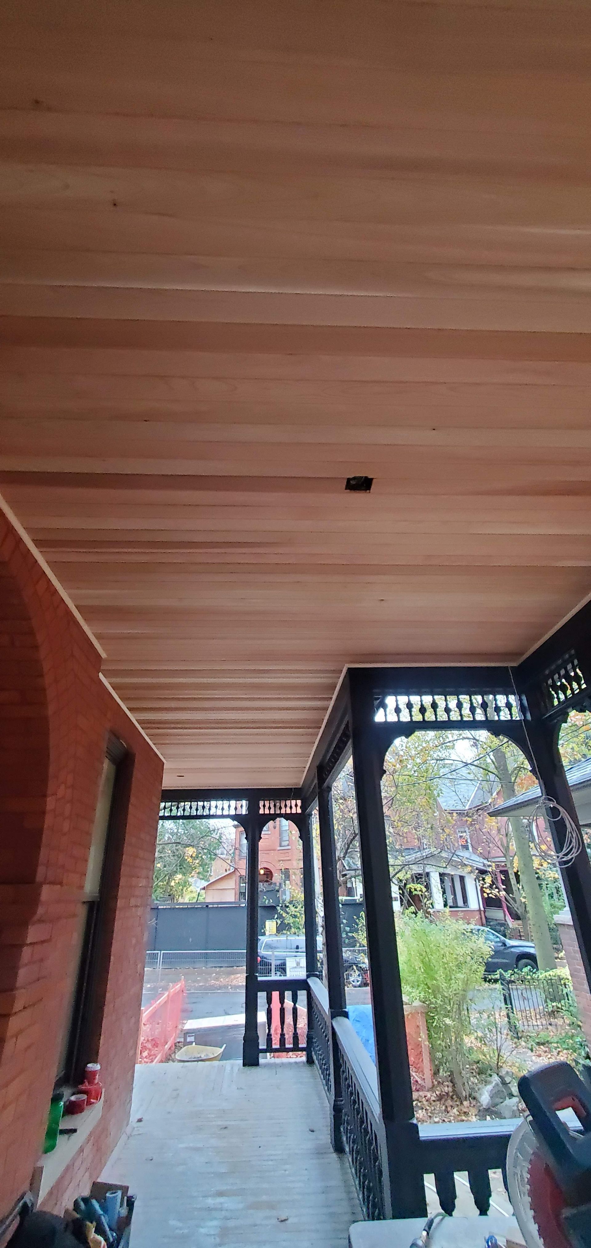 A porch with a wooden ceiling and stairs leading up to it.