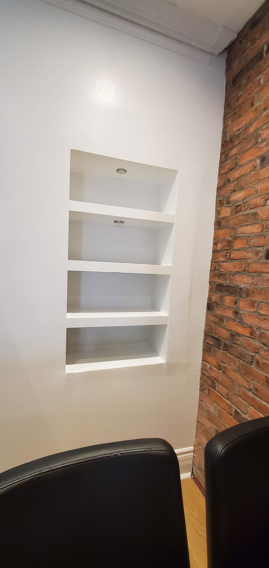 A room with a brick wall and a shelf in the wall.