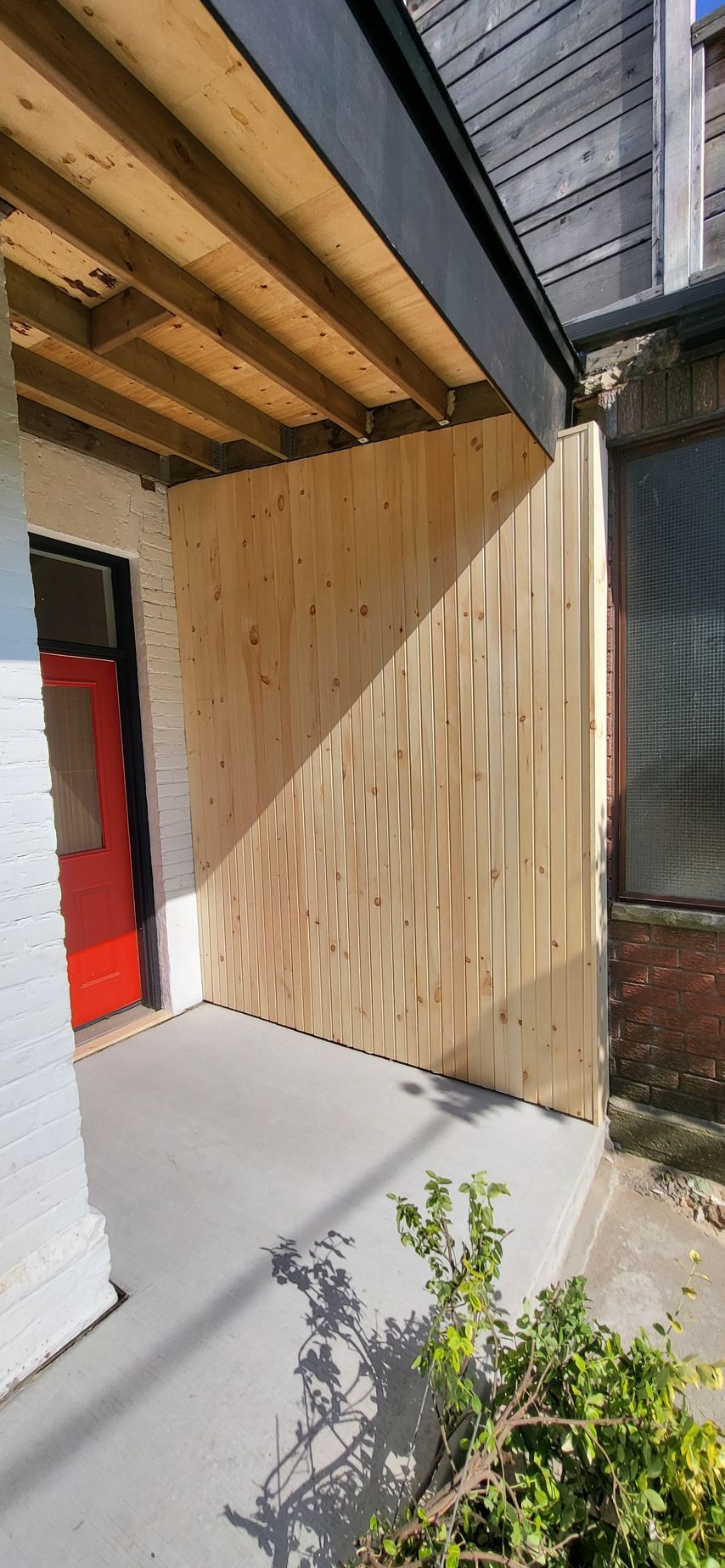 A porch with a wooden fence and a red door.