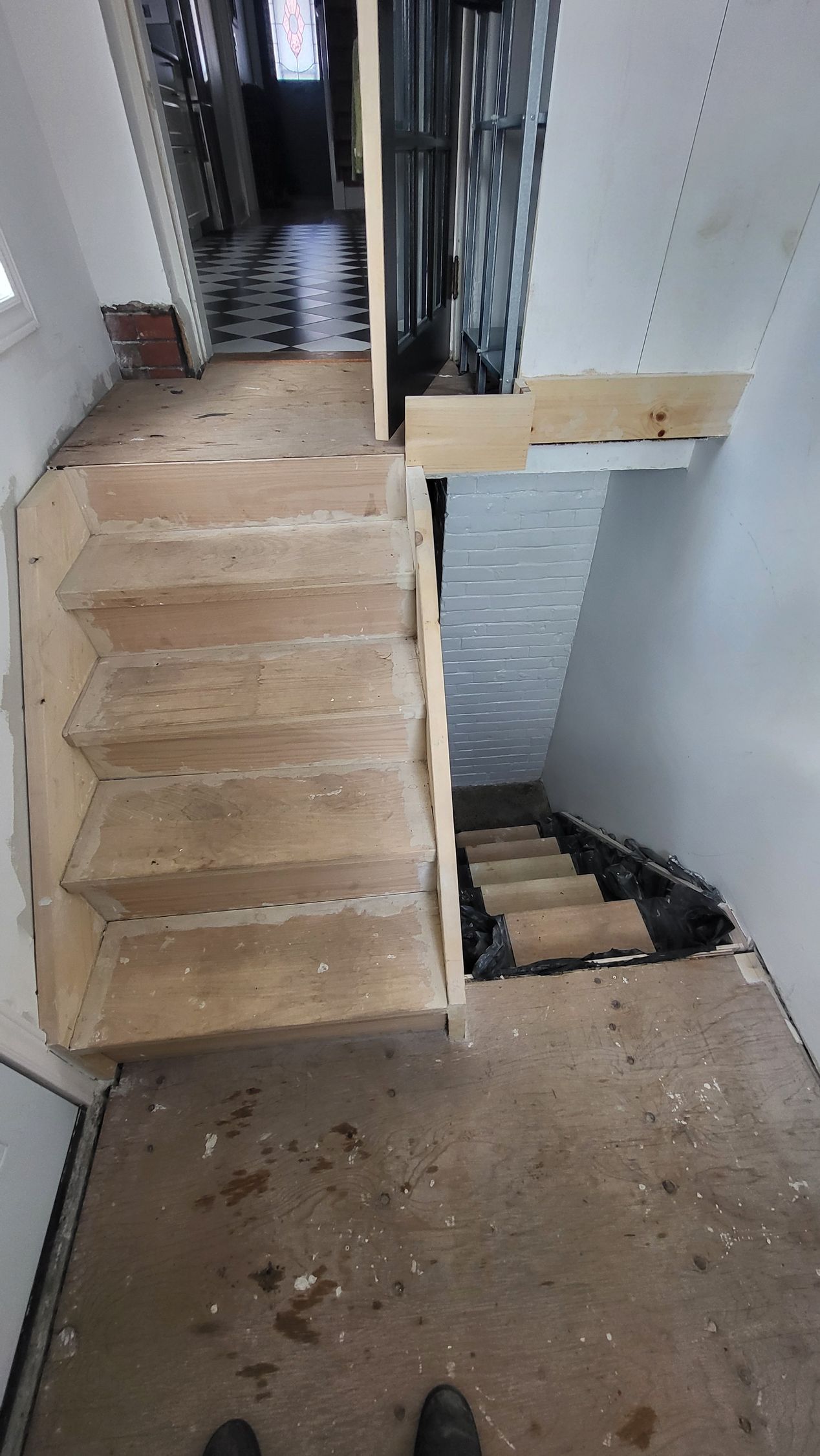 Interior view of unfinished stairs. Wooden steps and landing with open space leading downwards.