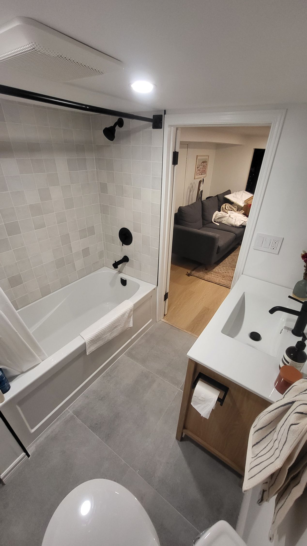 Bathroom with white tub, grey tile, black fixtures, and a shower curtain.