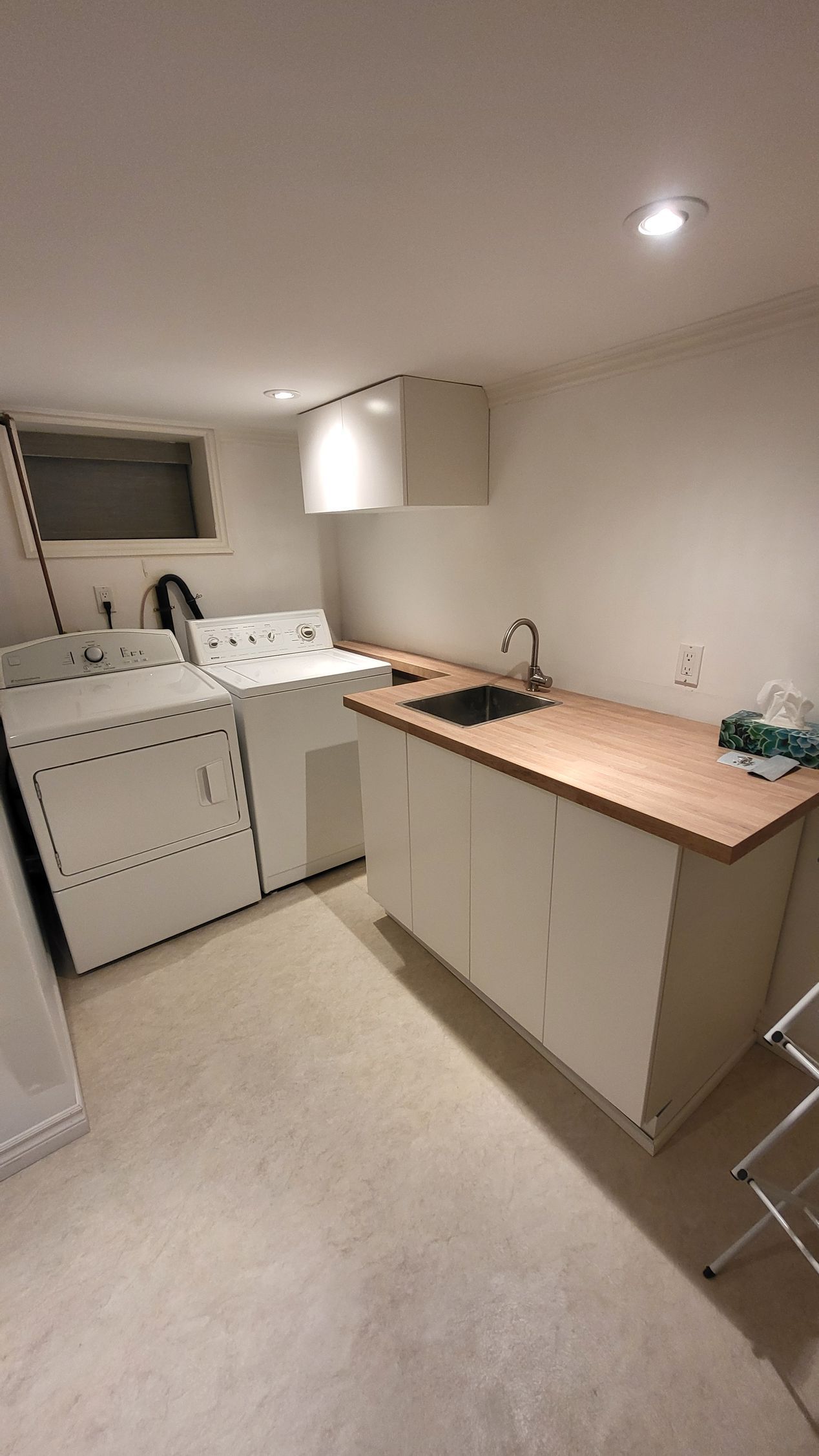 Laundry room with washing machine, dryer, sink, counter, and drying rack.