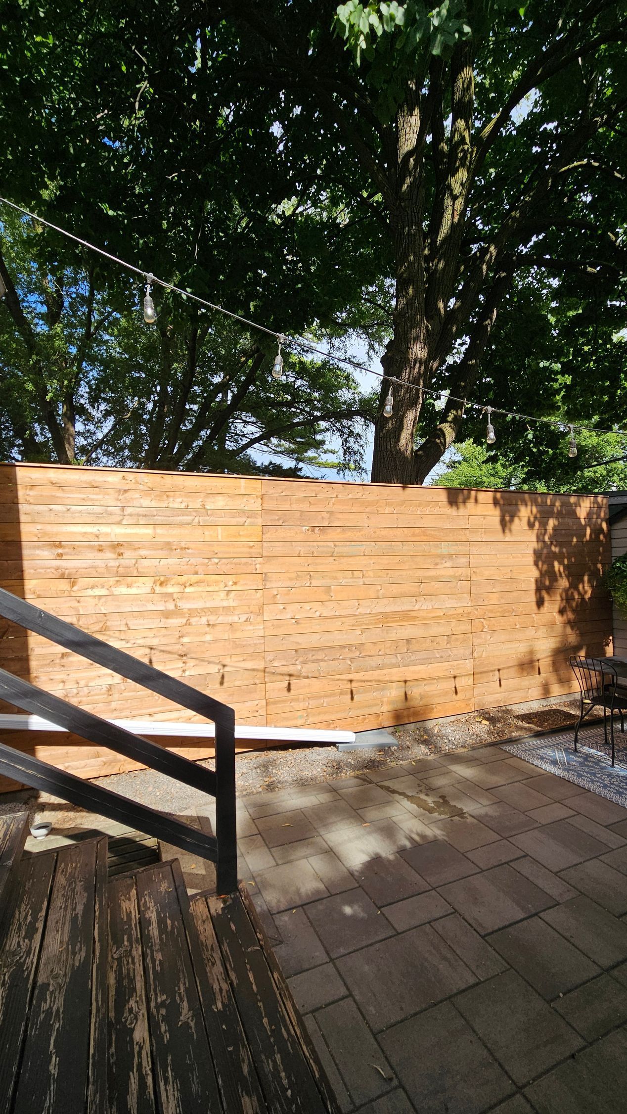 Wooden fence with a staircase and large tree in background.