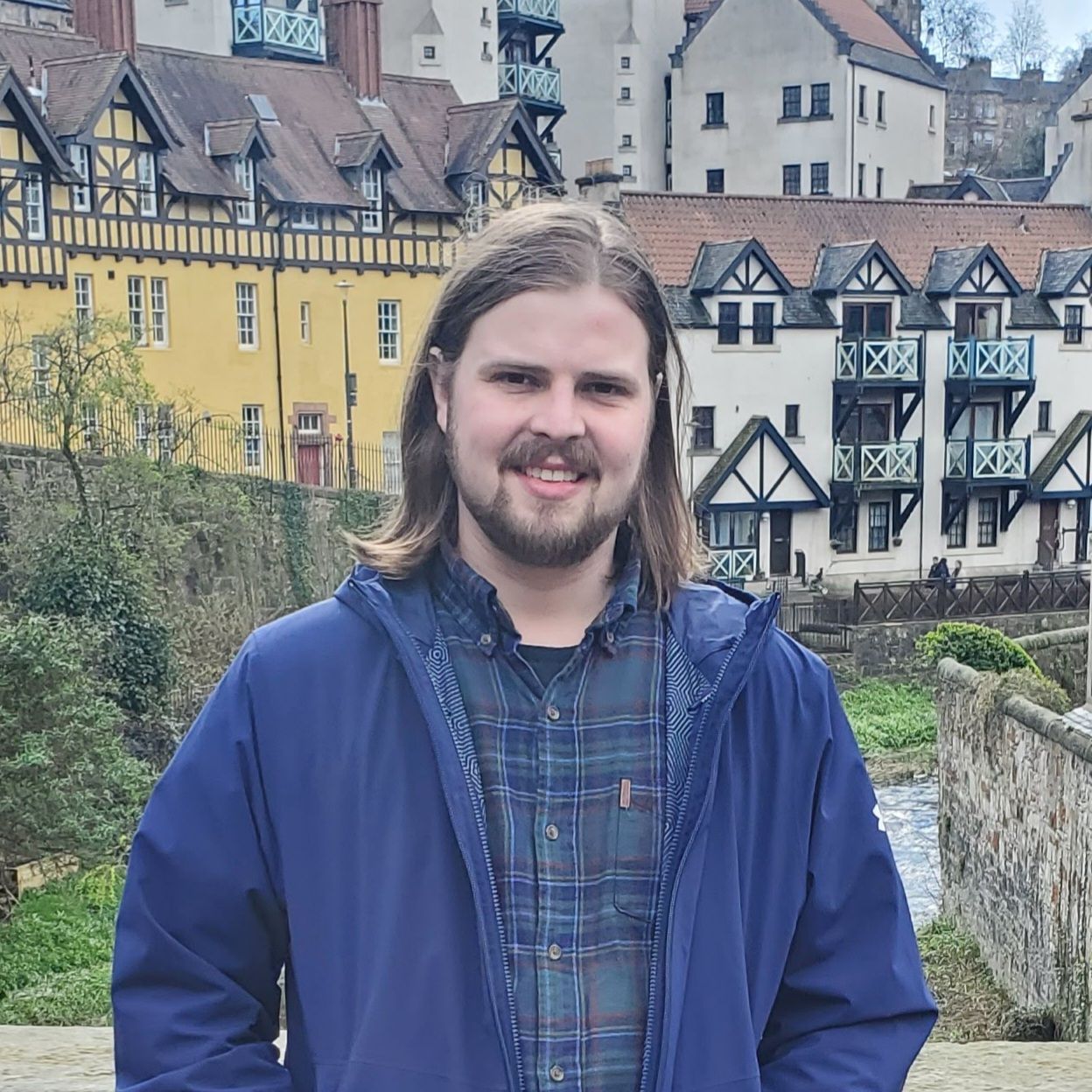 Person smiling outdoors with historic European-style buildings in the background