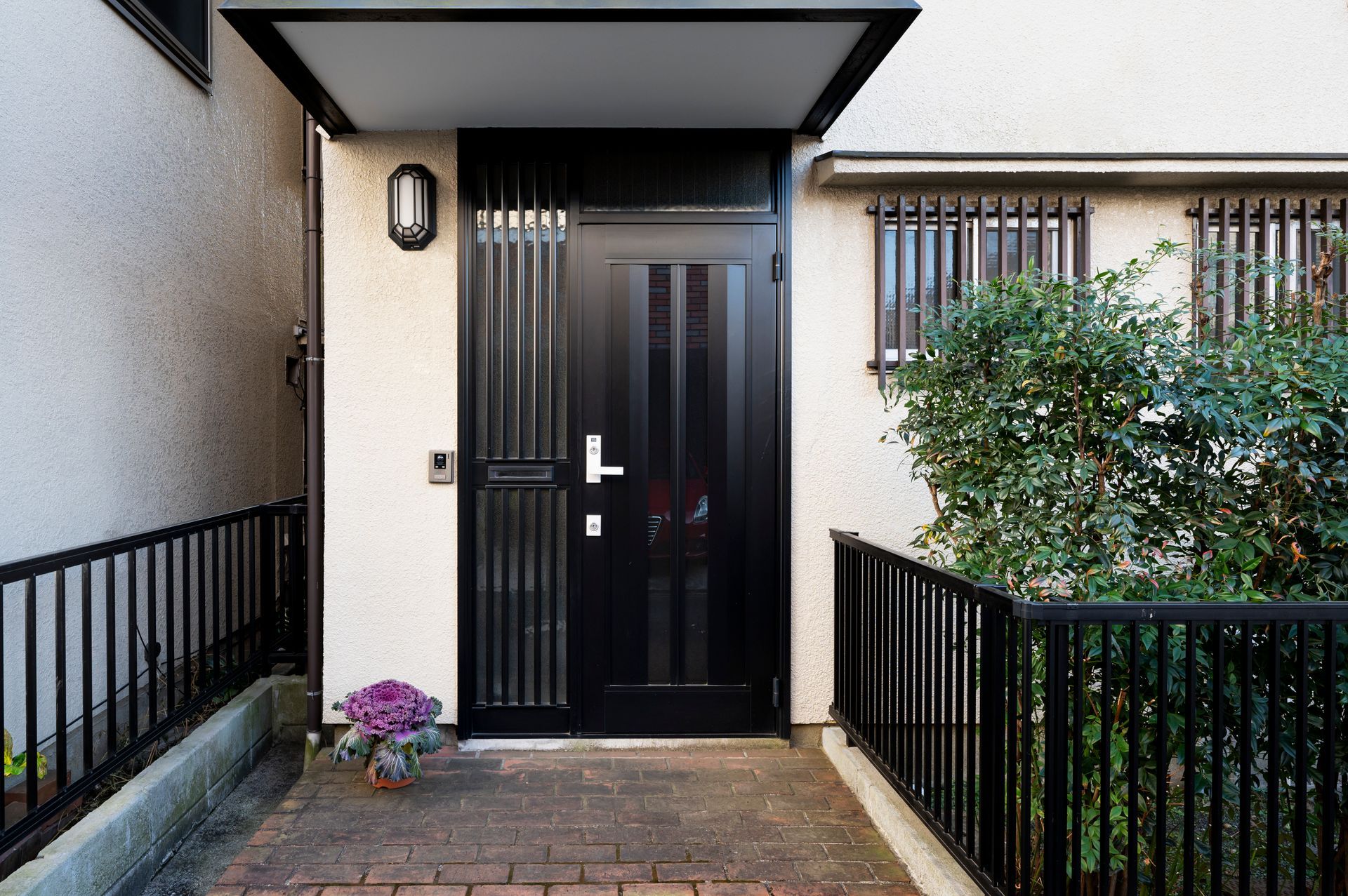 A black door is sitting on a brick walkway next to a fence.