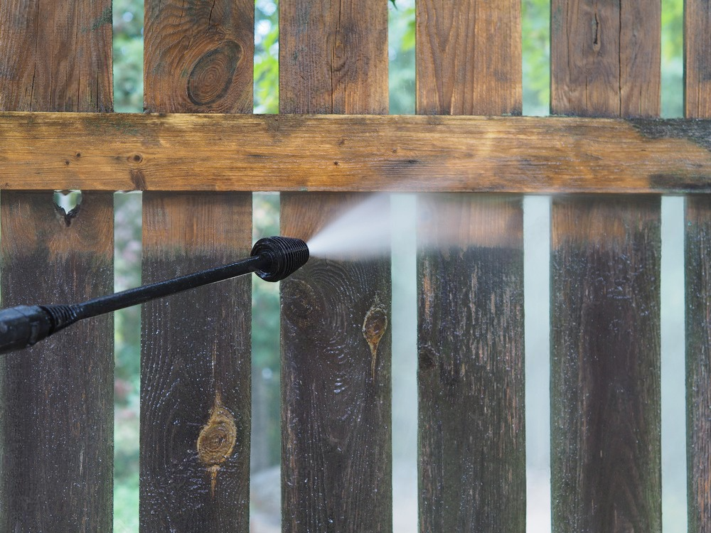 A close up of a high pressure washer spraying water on a concrete surface.