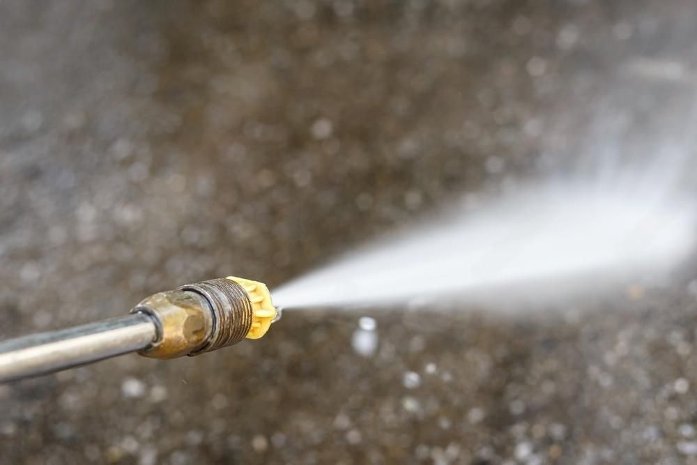 A close up of a high pressure washer spraying water on a concrete surface.