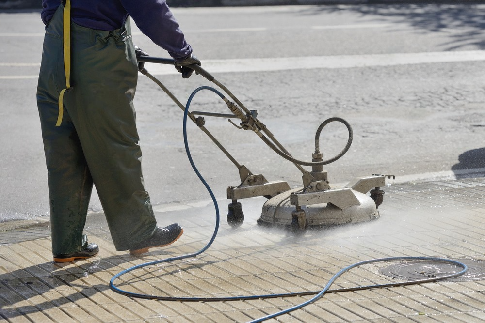 A man is using a machine to clean a sidewalk