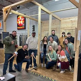 A group of people are posing for a picture while holding axes.