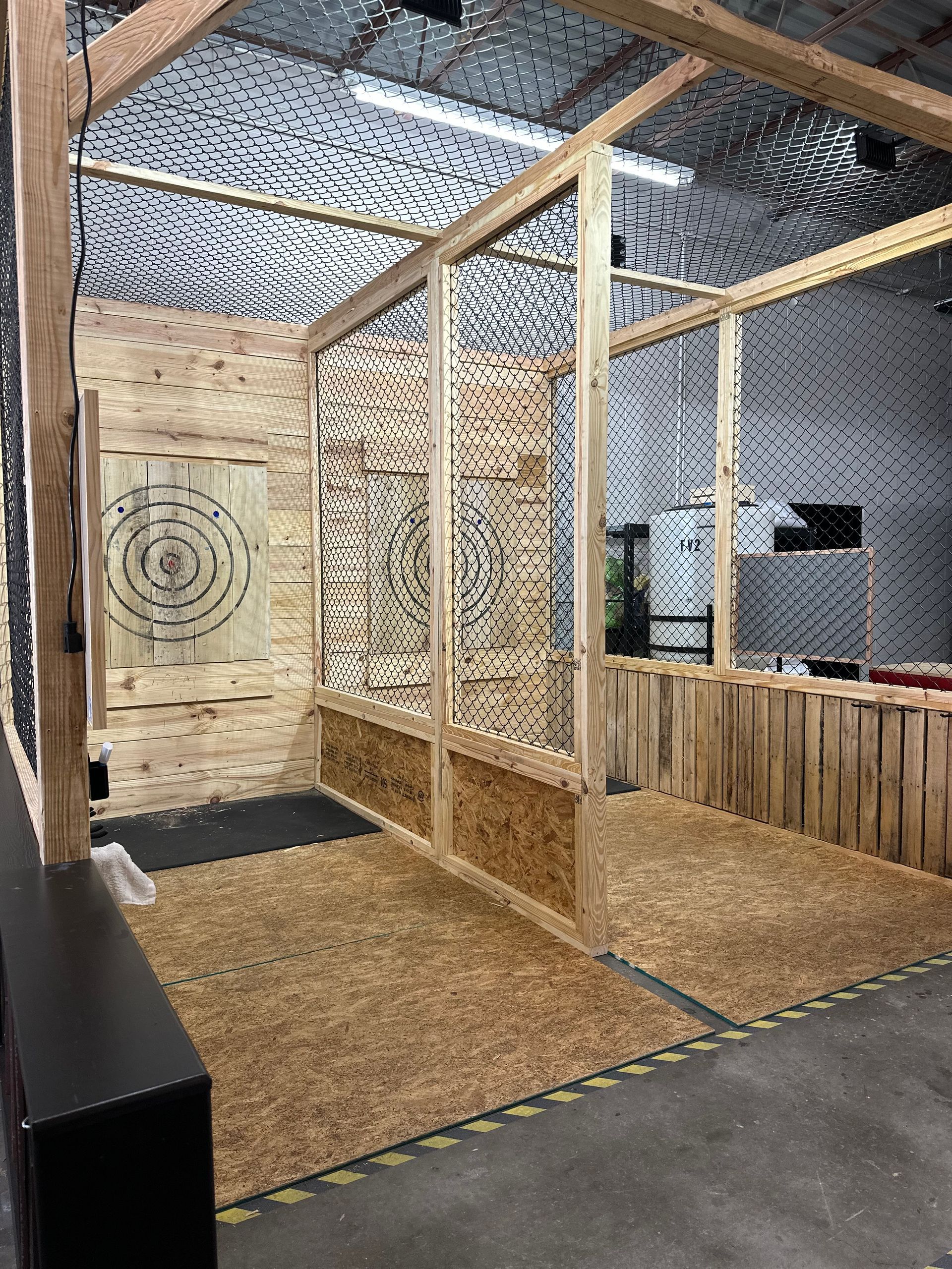 A room with a lot of axes and a target on the wall.