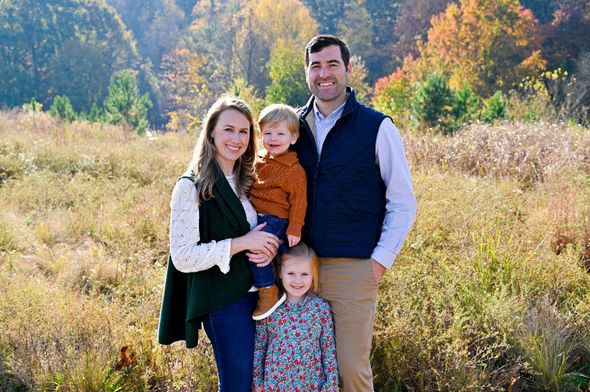 A family is posing for a picture while sitting on a blanket in a field.