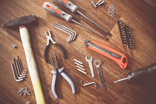 Assorted hand tools laid out on a wooden workbench, including hammers, pliers, screwdrivers, and wrenches.