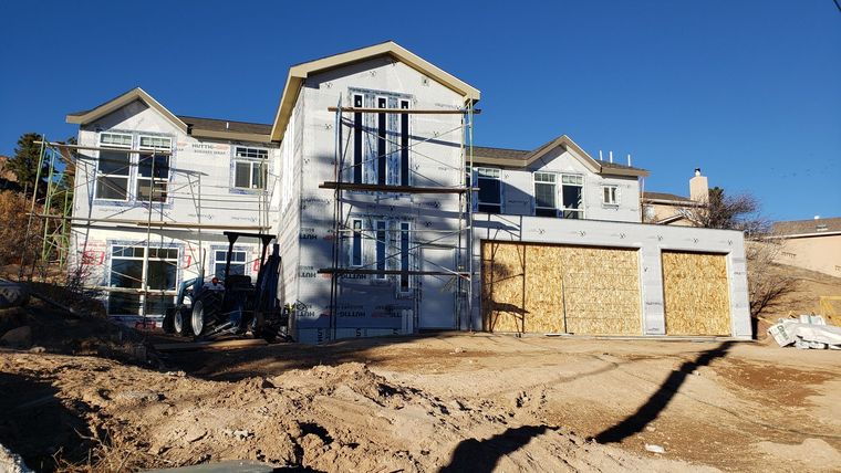 A small wooden cabin illuminated at night, featuring a lit stone pathway through a green lawn.
