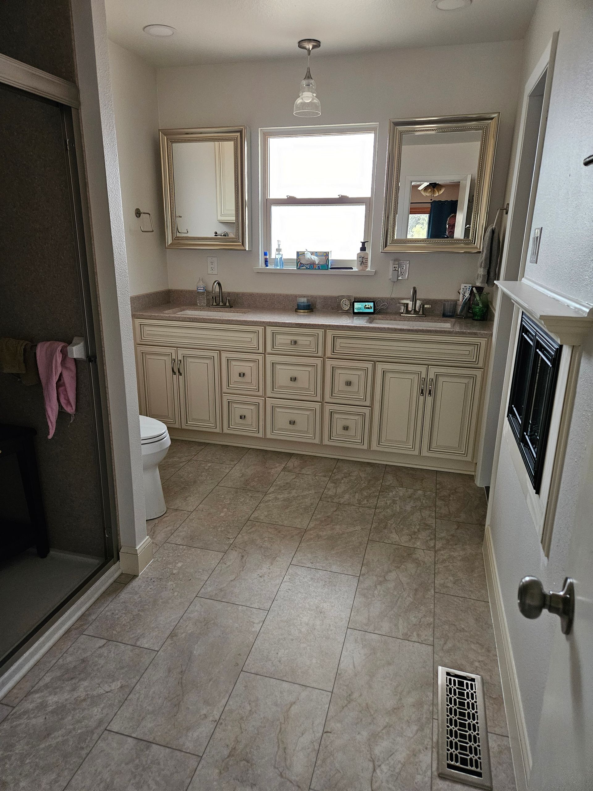 Bathroom with sink vanity, large mirrors, tiled floor, and shower stall