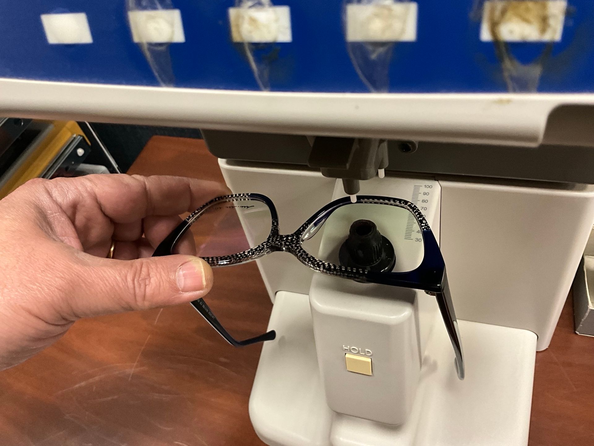 Persona che tiene in mano un paio di occhiali rossi, con altri due paia sullo sfondo, su uno sfondo bianco.