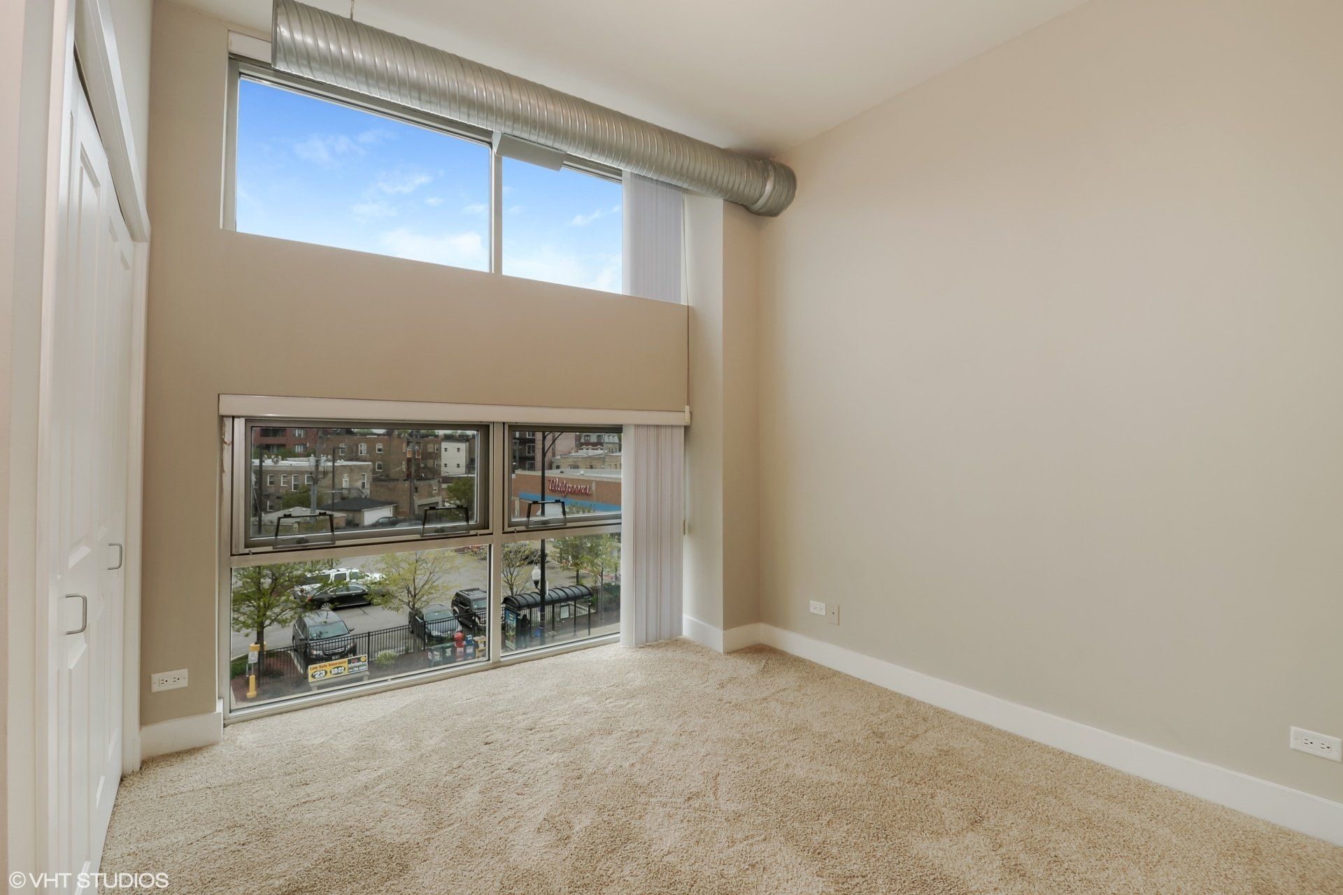 An empty room with a large window and a balcony at 2000 N Milwaukee Apartments.