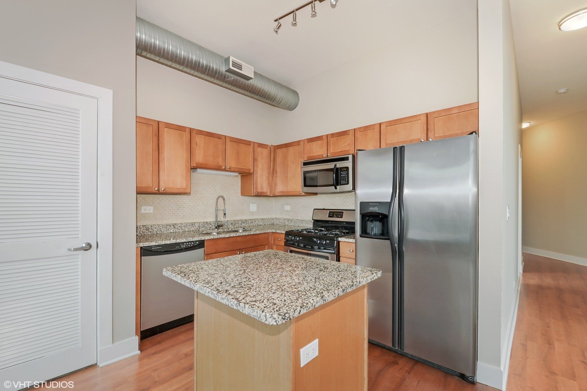 A kitchen with stainless steel appliances and granite counter tops at 2000 N Milwaukee Apartments.