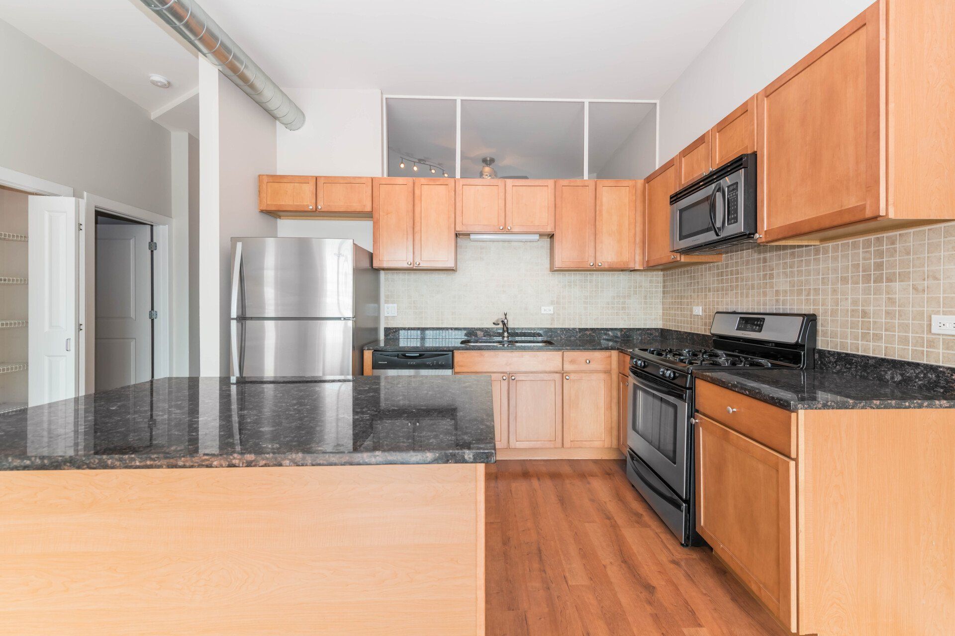 A kitchen with stainless steel appliances and wooden cabinets at 2000 N Milwaukee Apartments.