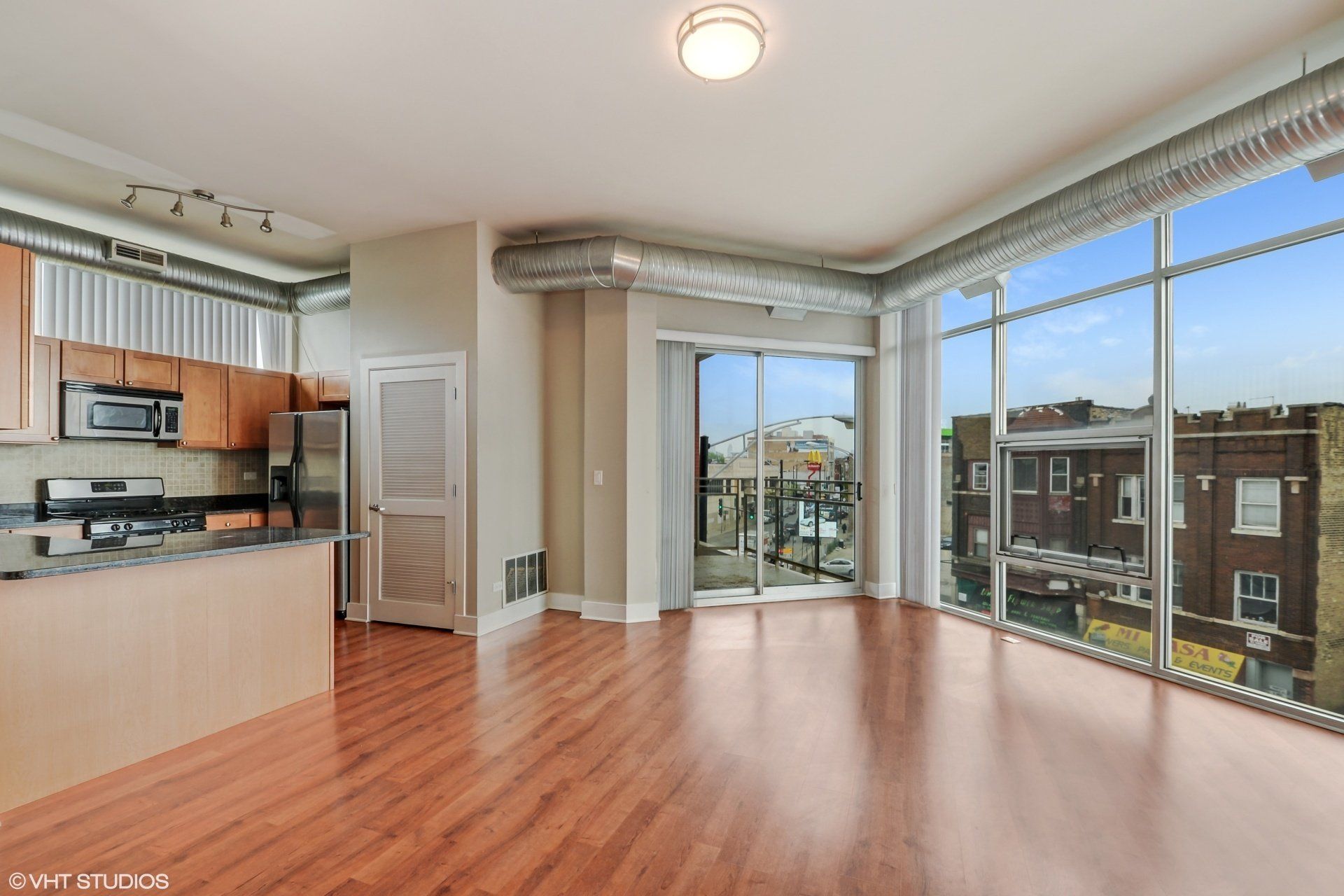 An empty apartment with a lot of windows and hardwood floors at 2000 N Milwaukee Apartments.