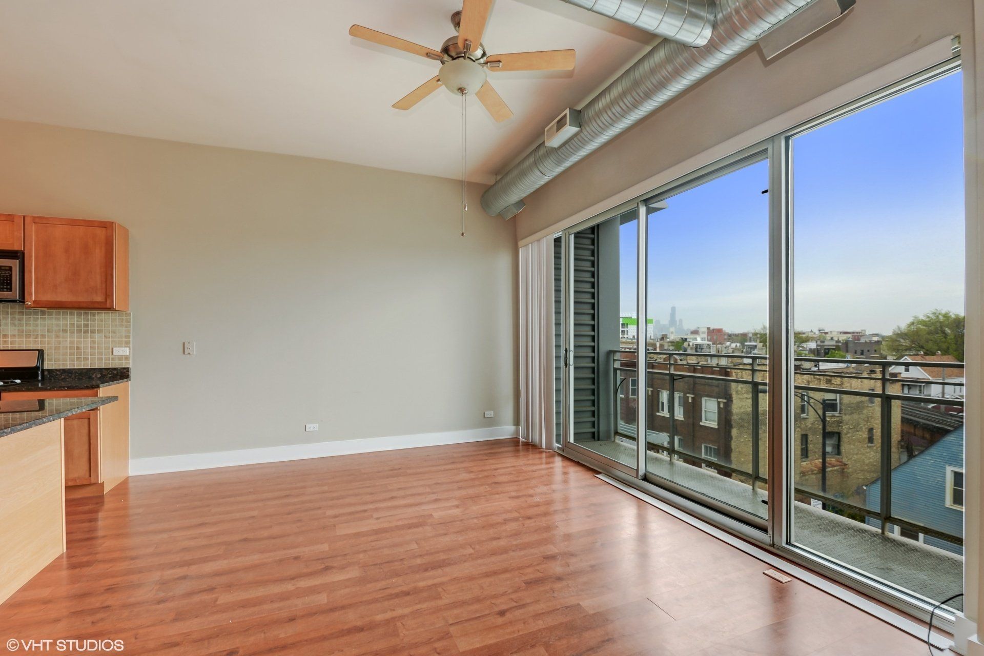 An empty apartment with hardwood floors and a ceiling fan at 2000 N Milwaukee Apartments.