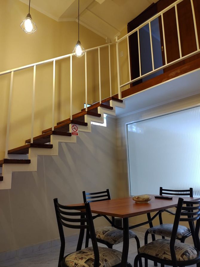 La escalera conduce al loft sobre la mesa del comedor y sillas, con dos lámparas colgantes.