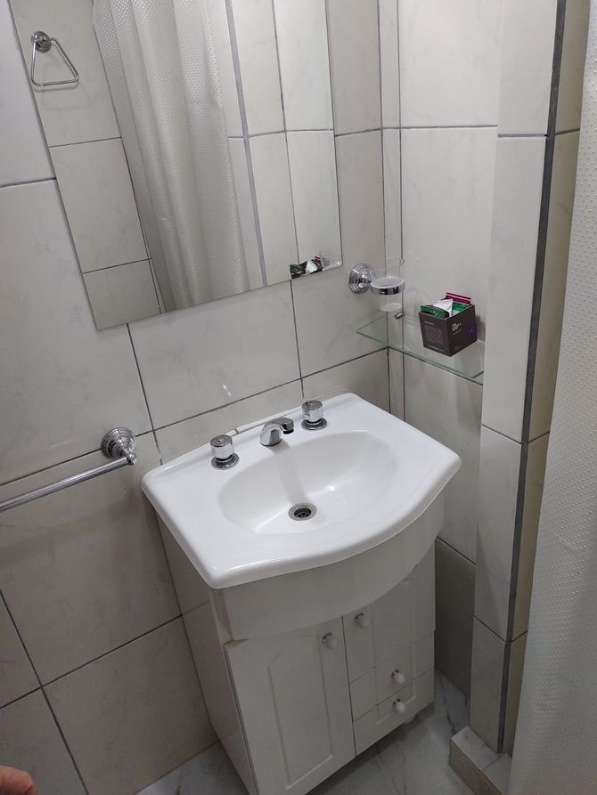 Baño con lavabo y mueble blanco, espejo y toallero.