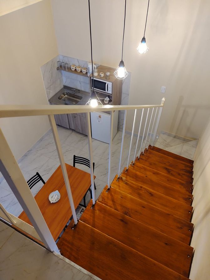 Escalera de madera que conduce a una zona de cocina/comedor con luces en el techo.