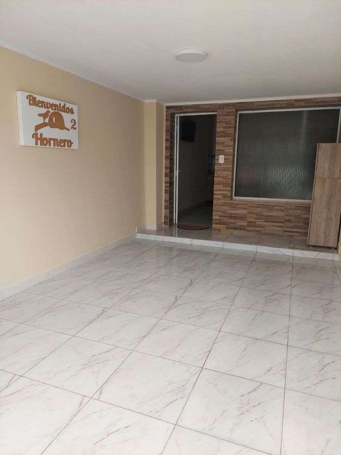 Habitación vacía con piso de baldosas, puerta y ventana con pared de ladrillo decorativa.