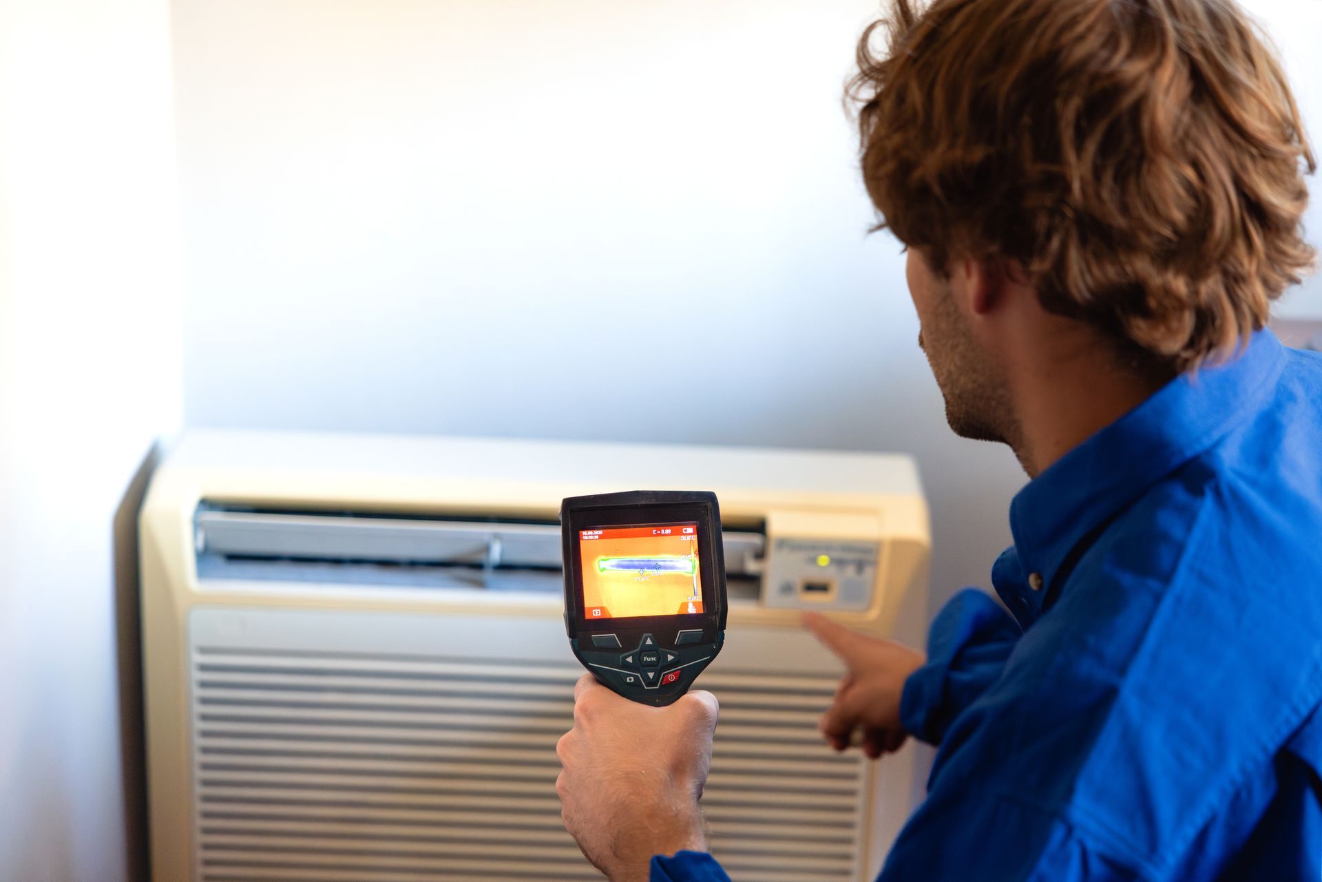 Technician checking air conditioner with thermal camera.
