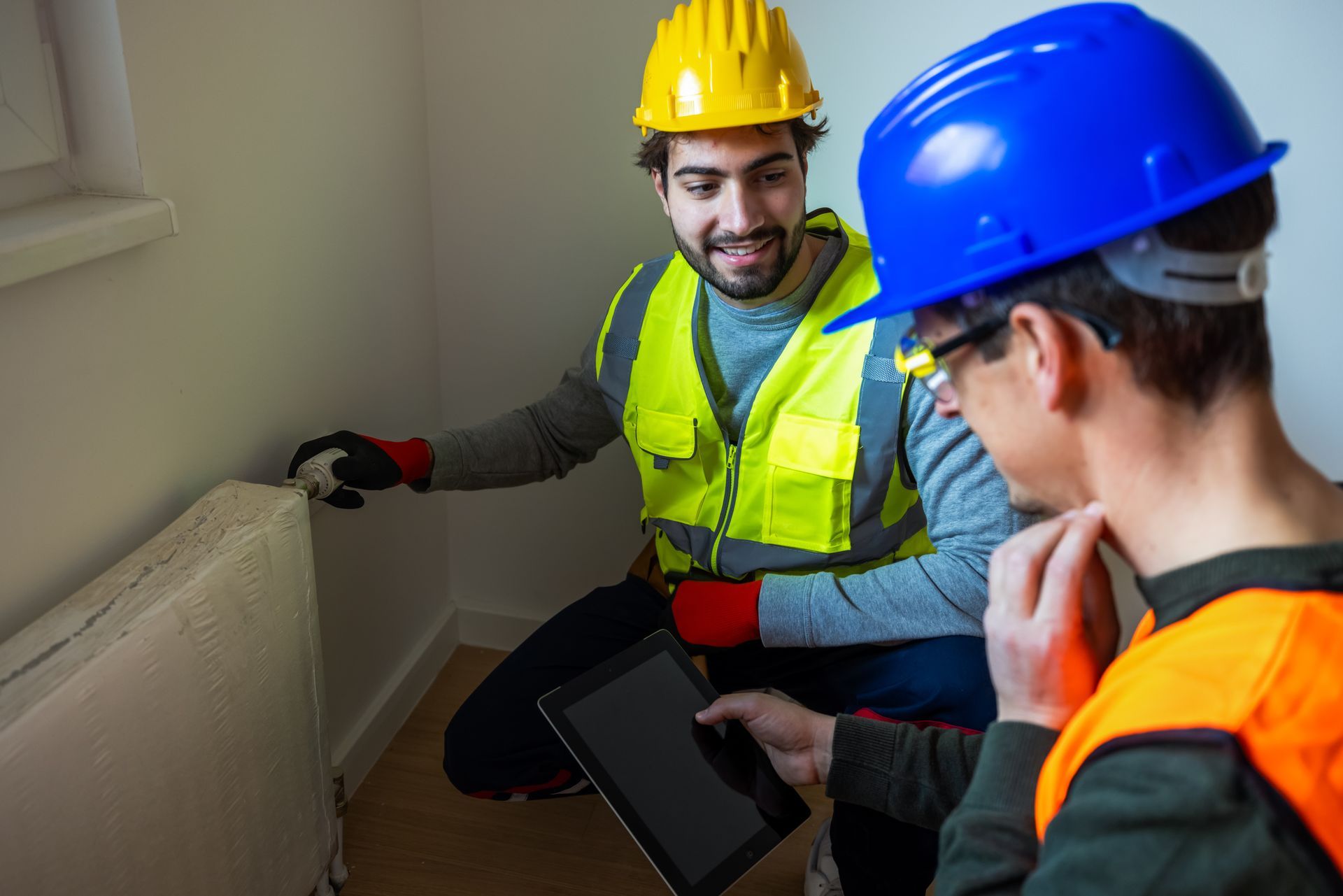 Two construction workers inspecting a radiator installation