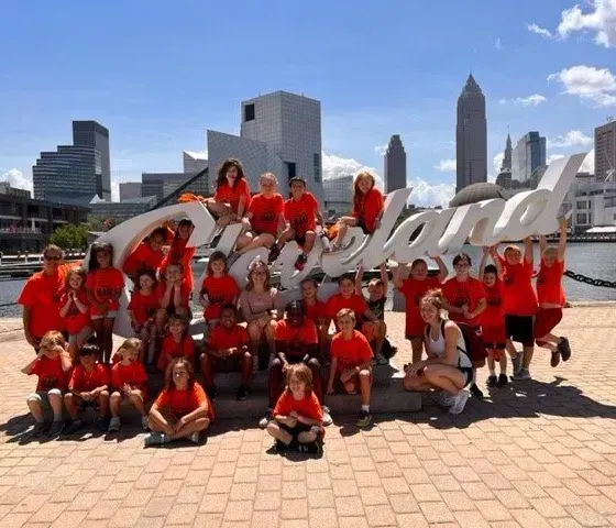A large group of people posing in front of a cleveland sign