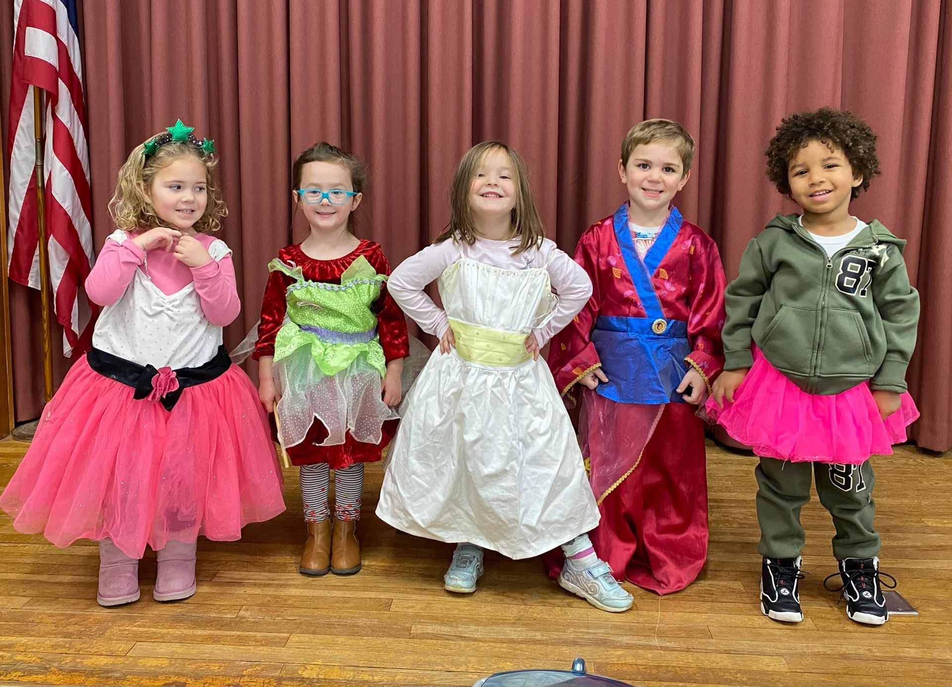 A group of children dressed in costumes are standing next to each other on a stage.