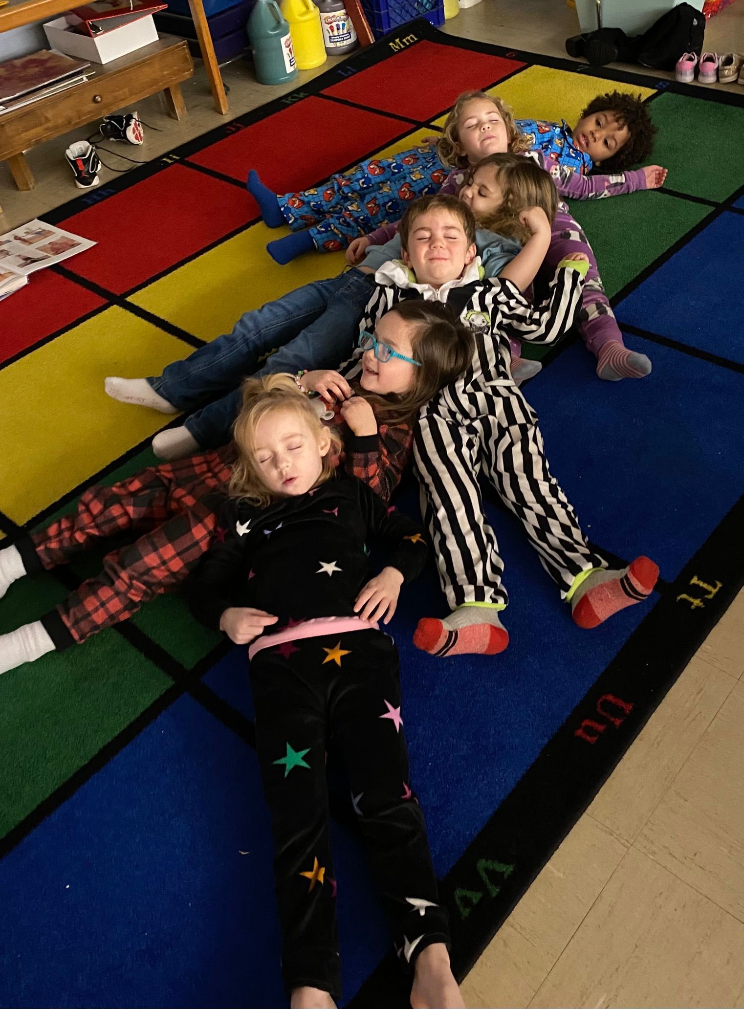 A group of children are laying on a colorful rug