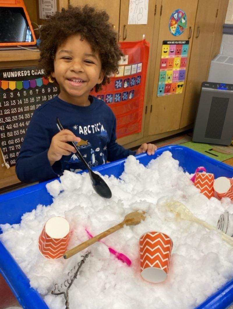 A young boy is playing in a snowy sensory bin