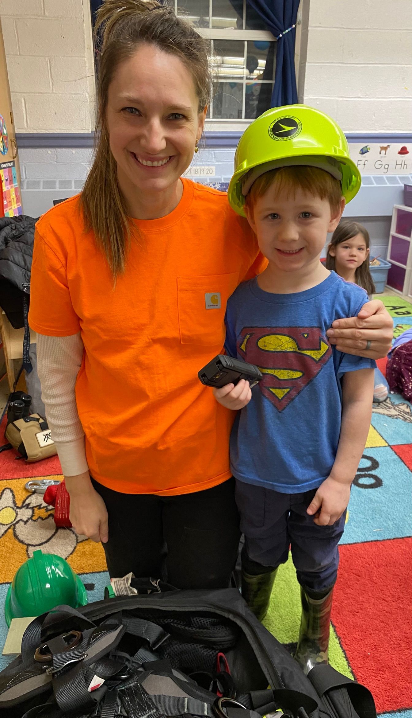 A woman is standing next to a young boy wearing a hard hat.