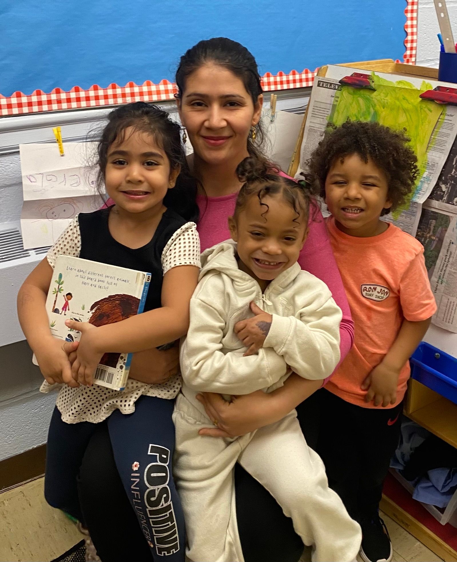 A woman in a pink shirt is holding three children