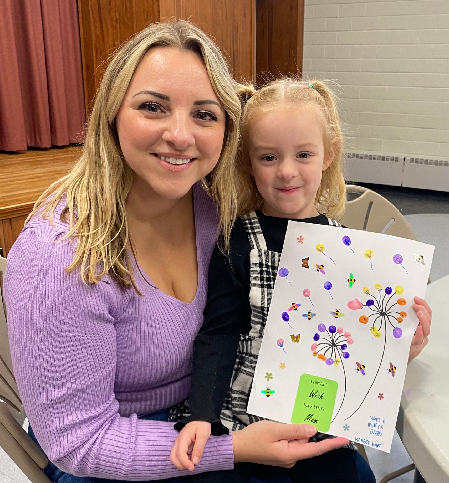 A woman and a little girl are holding a drawing of dandelions.