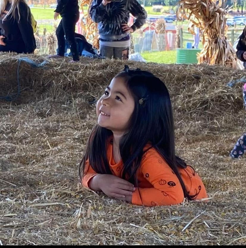 A little girl is laying in a pile of hay